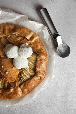 Delicious apple galette served with ice cream on light grey textured table, top view