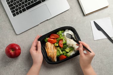 Ofis çalışanı iş yerinde öğle yemeği yiyor.