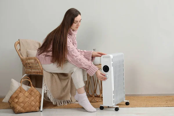現代のポータブル電気ヒーターの温度を屋内で調整する若い女性 — ストック写真