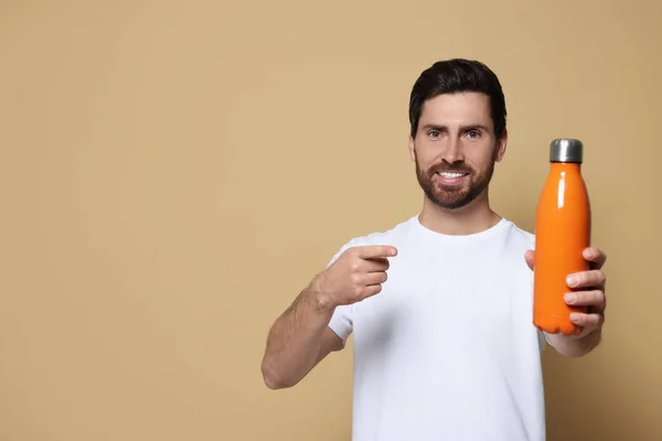 Hombre Apuntando Botella Termo Naranja Sobre Fondo Beige Espacio Para —  Fotos de Stock
