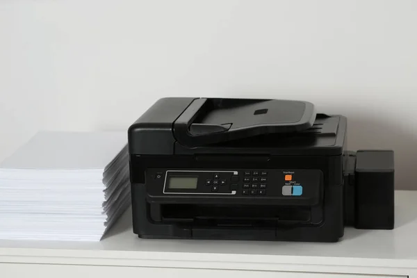 Modern printer and paper sheets on white table indoors