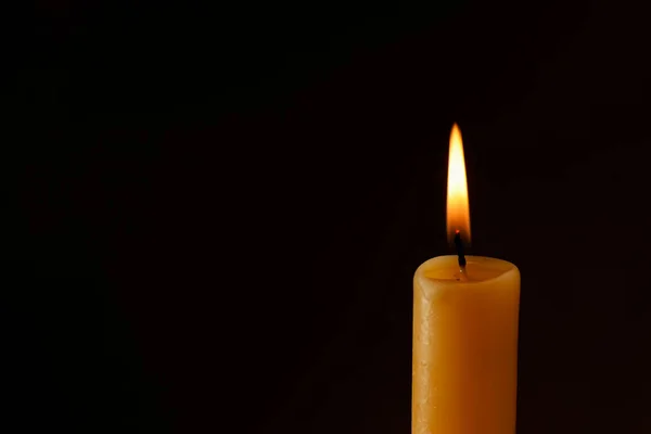 Burning church wax candle on dark background, closeup. Space for text