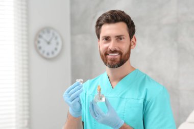 Dişçi klinikte diş implantının eğitici modelini tutuyor. Metin için boşluk