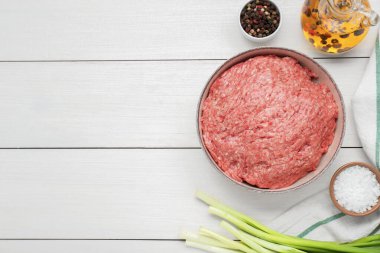 Bir kase taze kıyma ve malzemeler beyaz ahşap masada, düz yerde. Metin için boşluk