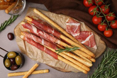 Lezzetli Grissini çubukları prosciutto ve aperatifler kahverengi masada, düz yatar