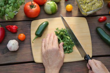 Ahşap masada salsa sosu için kişniş kesen kadın.