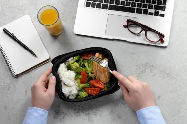 Ofis çalışanı iş yerinde öğle yemeği yiyor.