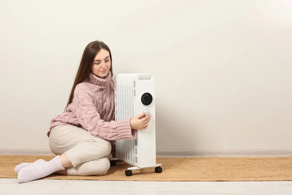 Mujer Joven Ajustando Temperatura Calentador Eléctrico Moderno Cerca Pared Beige —  Fotos de Stock