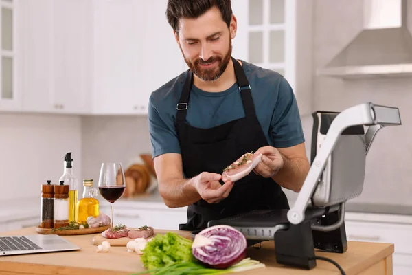Człowiek Robi Kolację Podczas Oglądania Online Gotowania Kurs Pomocą Laptopa — Zdjęcie stockowe