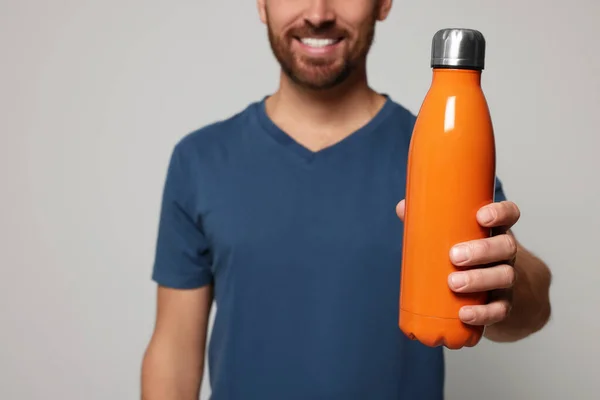 Hombre Con Termo Botella Naranja Sobre Fondo Gris Claro Primer —  Fotos de Stock
