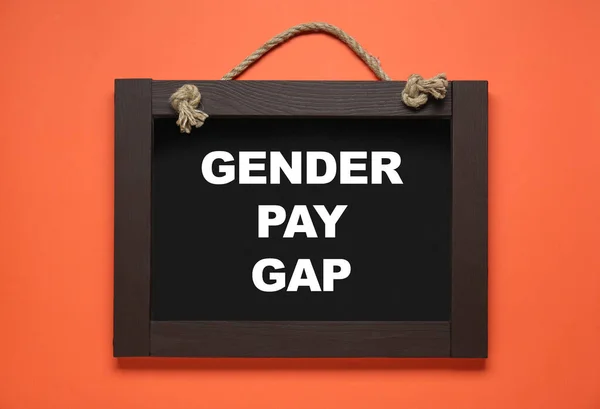Blackboard with words Gender Pay Gap on orange background, top view