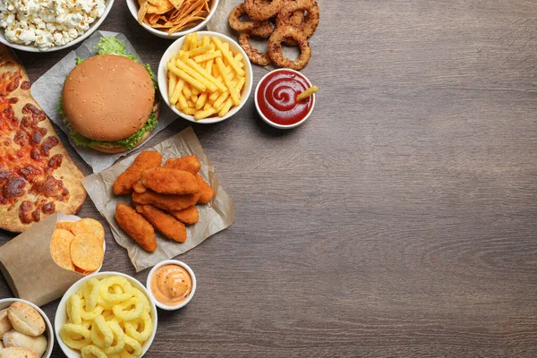 stock image French fries, onion rings and other fast food on wooden table, flat lay with space for text