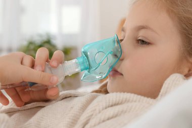 Yatak odasında nebulizör kullanan küçük kız, yakın plan.