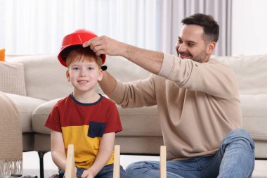 Baba evde oğluna sert şapka takıyor. Onarım işi