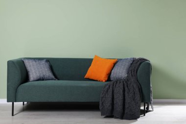 Dekoratif yastıklı ve battaniyeli rahat bir kanepe.