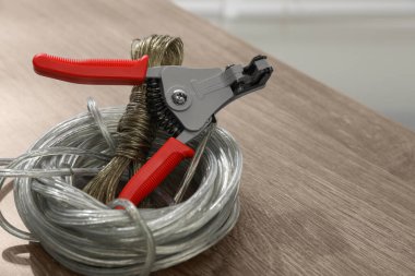Cutters and stripped wire on wooden table, closeup. Space for text