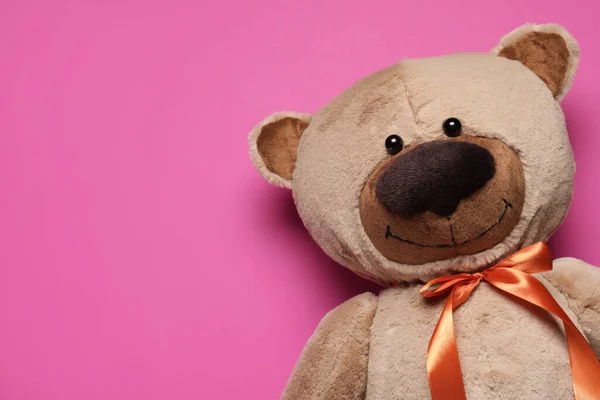 Cute teddy bear on pink background, top view. Space for text