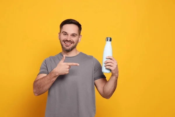 Hombre Feliz Apuntando Botella Termo Contra Fondo Naranja —  Fotos de Stock