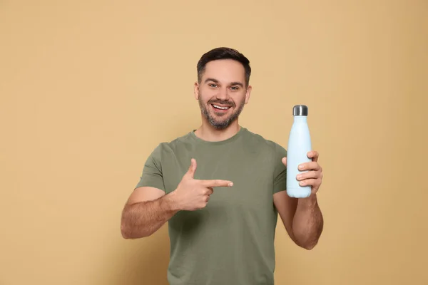 Ευτυχισμένος Άνθρωπος Δείχνοντας Θερμοφόρα Μπουκάλι Μπεζ Φόντο — Φωτογραφία Αρχείου