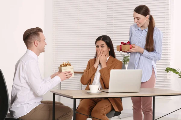 Colleagues presenting gifts to woman in office