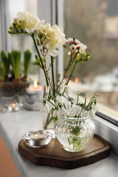 不同美丽的春花和窗台上的蜡烛在室内 — 图库照片