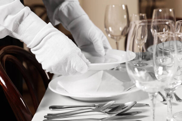 Woman setting table in restaurant, closeup. Professional butler courses
