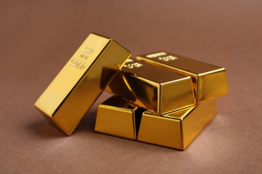 Kahverengi arka planda bir sürü parlak altın külçeler