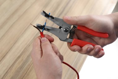 Profesyonel elektrikçi, ahşap masada kablo söküyor.