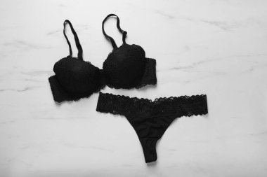 Beyaz mermer arka planda zarif siyah kadın iç çamaşırları.