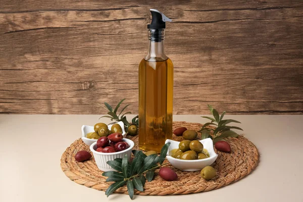 米色桌子上的一壶油 橄榄和树枝 — 图库照片