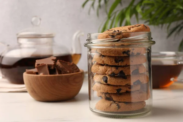 Glasgefäß Mit Leckeren Schokoladenkeksen Und Tee Auf Weißem Marmortisch — Stockfoto