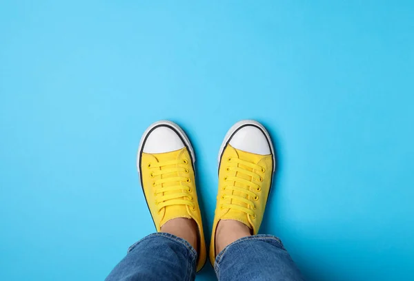 Woman in stylish gumshoes on light blue background, top view