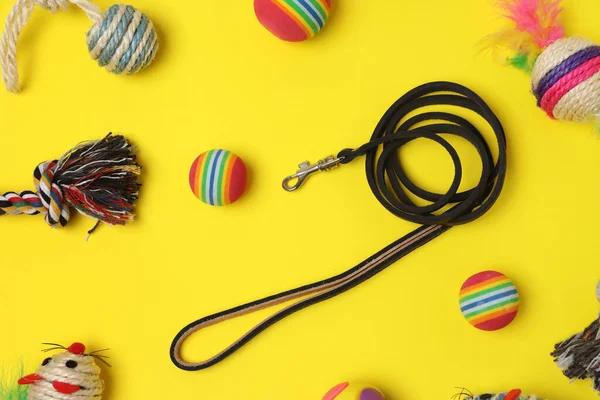 Flat lay composition with pet leash and toys on yellow background