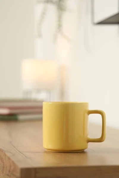 Yellow mug on wooden table indoors. Mockup for design