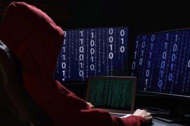 Hacker karanlık odada bilgisayarlarla çalışıyor. Siber saldırı