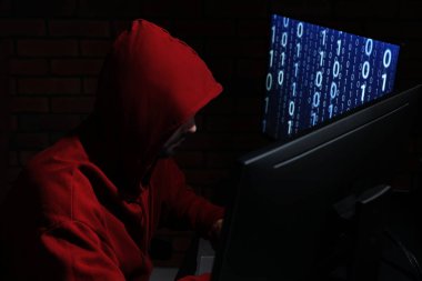 Hacker karanlık odada bilgisayarlarla çalışıyor. Siber saldırı