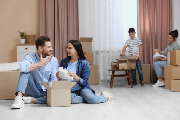幸せな家族は新しい家に定住し 箱を開梱しています 移動日 — ストック写真