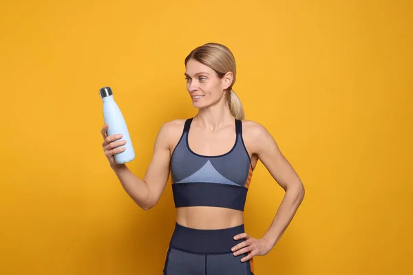 Sportlerin Mit Thermoflasche Auf Gelbem Hintergrund — Stockfoto