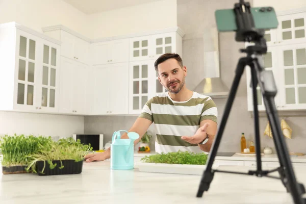 stock image Teacher with microgreens and watering can conducting online course in kitchen. Time for hobby