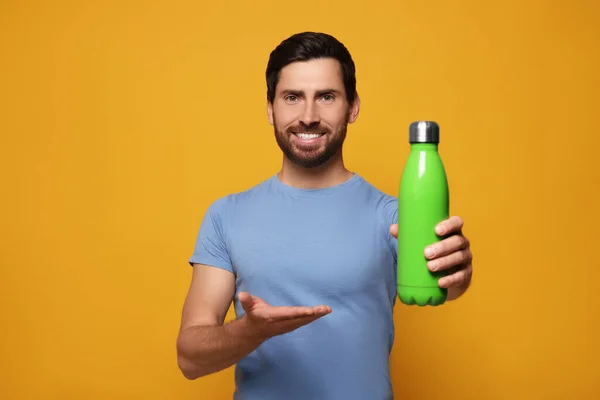 Hombre Con Termo Botella Verde Sobre Fondo Naranja —  Fotos de Stock