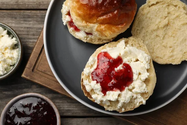 stock image Freshly baked soda water scones with cranberry jam and butter on wooden table, flat lay