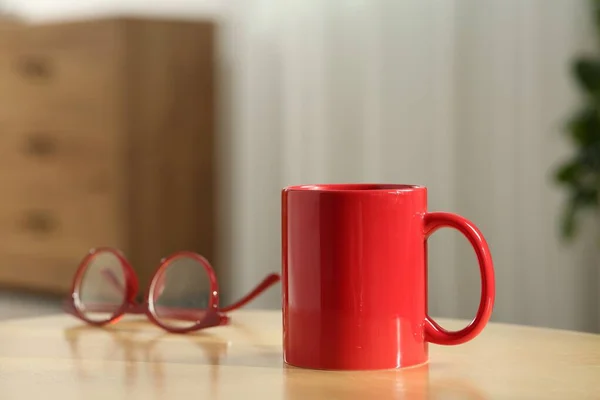 室内木制桌子上的红色杯子和眼镜 用于设计的模型 — 图库照片