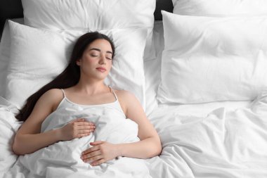 Güzel genç kadın yumuşak yatakta uyuyor.