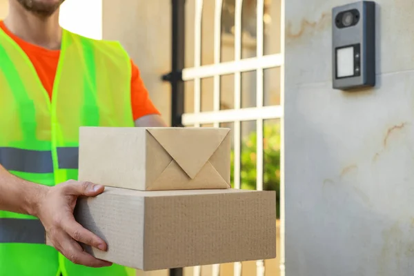 stock image Courier in uniform with two parcels outdoors, closeup