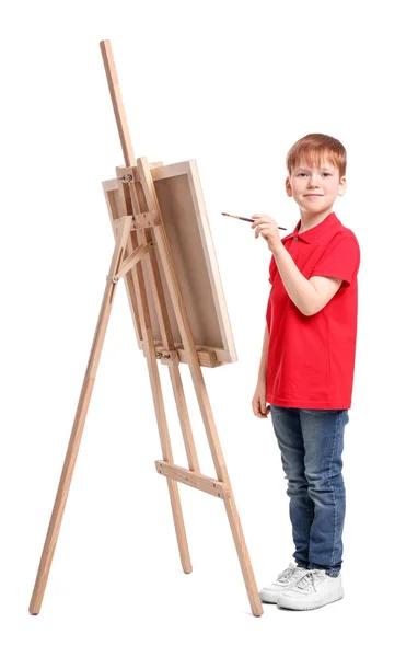 stock image Little boy painting against white background. Using easel to hold canvas