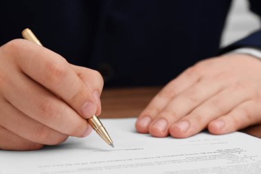 Man signing document at table, closeup view