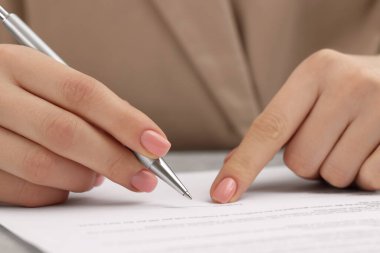 Woman signing document at table, closeup view