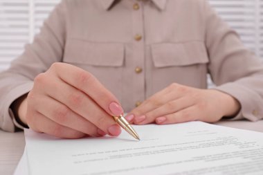 Woman signing document at table, closeup view