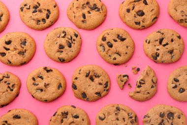 Pembe arka planda bir sürü çikolata parçalı kurabiye, düzlük.