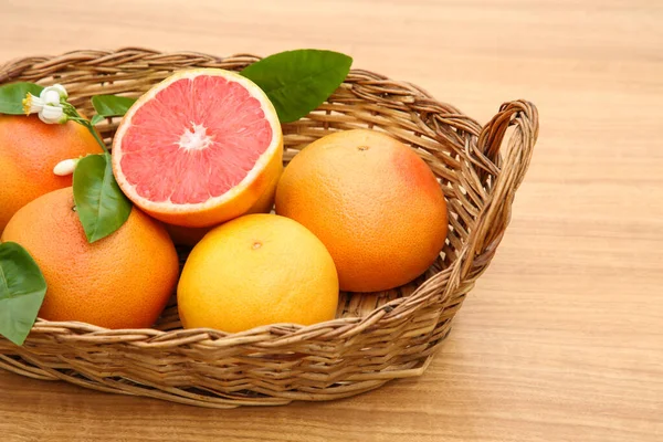 Weidenkorb Mit Frischen Reifen Grapefruits Und Grünen Blättern Auf Holztisch — Stockfoto